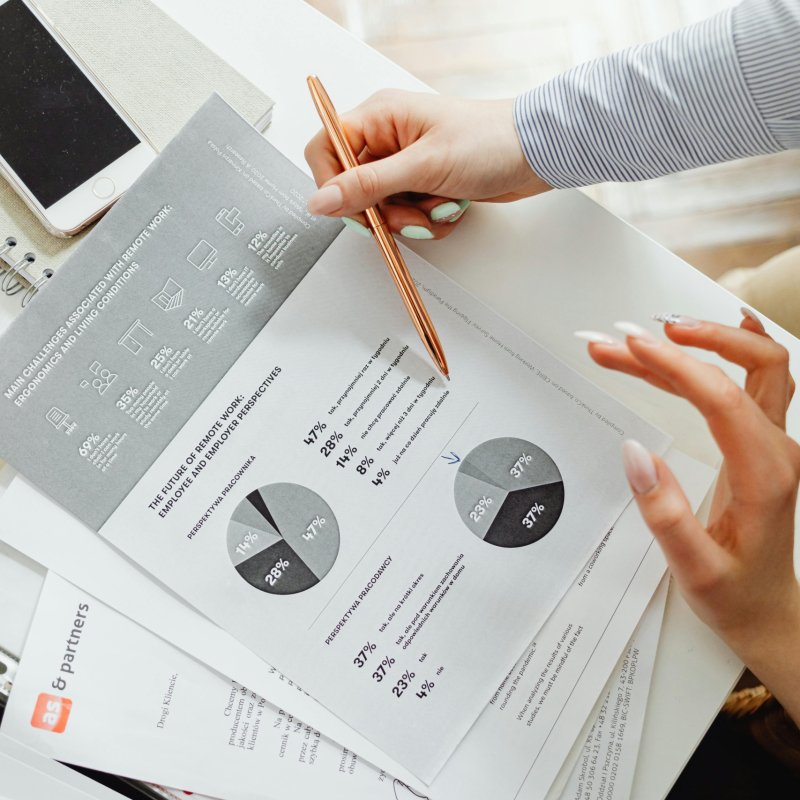 Close-up of businesswoman analyzing financial reports using pie charts in an office setting.